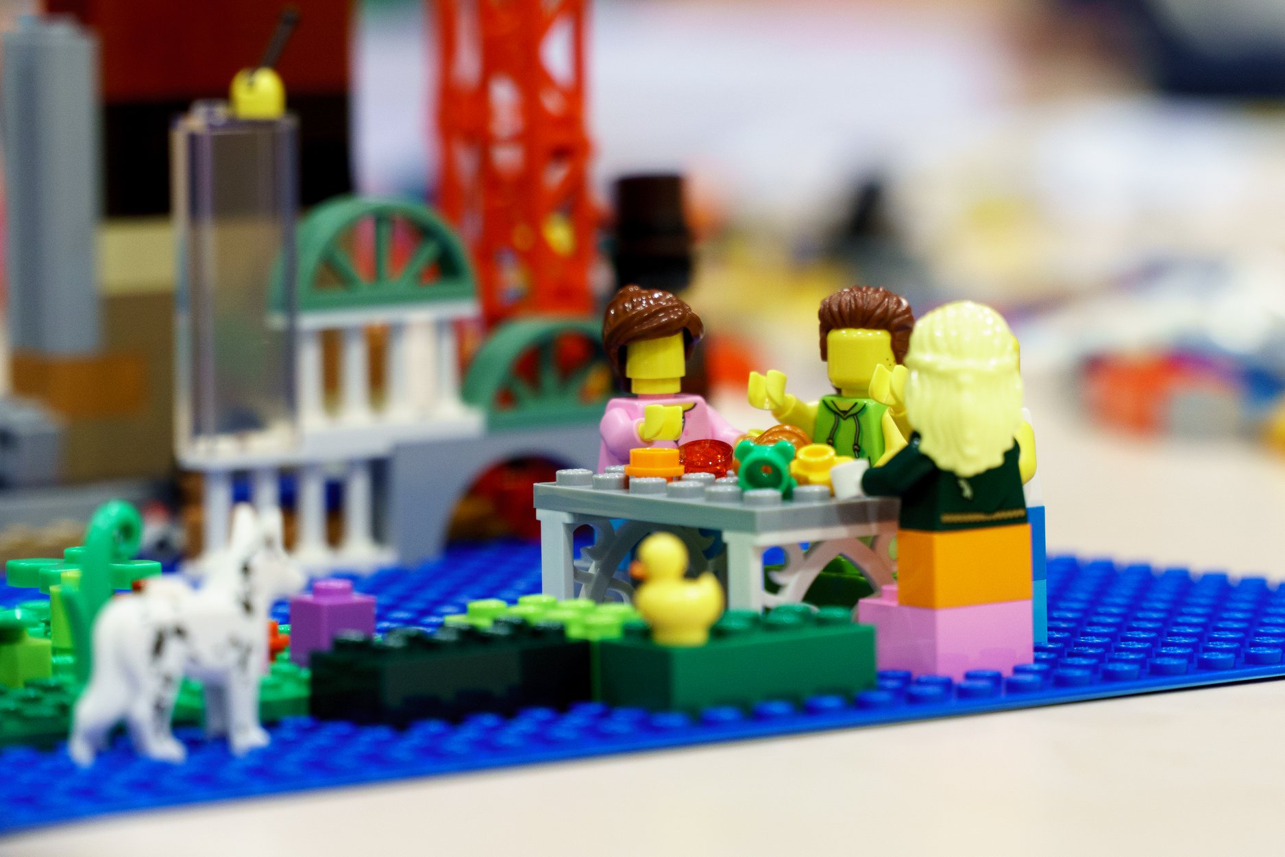 Zdjęcie przedstawiające budowlę z klocków lego, na pierwszym planie postaci siedzące przy wspólnym stole